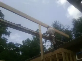 Carpenter setting a ridge beam over a new addition frame — Ice Dam Removal by Roofing Brothers in Bitely
