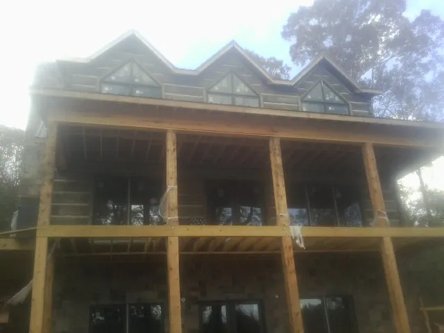 Dormers and porch framing on a large log home under construction — Roof Coating work by our crew in Bitely