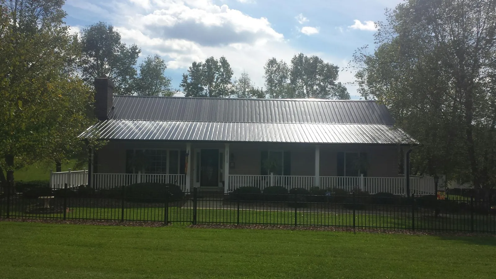 Gray metal roof on a brick ranch with a full width front porch — Gutter Guard Installation work by our crew in Bitely