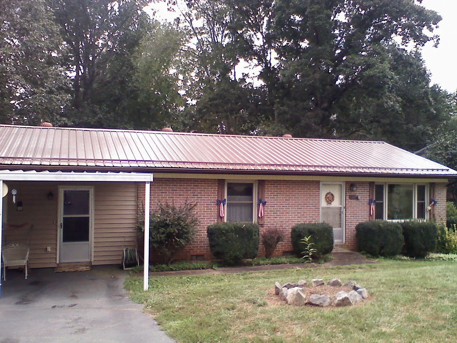 Bronze metal roof and carport on a brick ranch home — Roof Repair work by our crew in Bitely